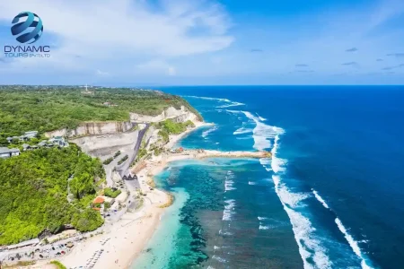 Aerial view of Kuta Beach Bali with turquoise waters, lush cliffs, and winding coastal road