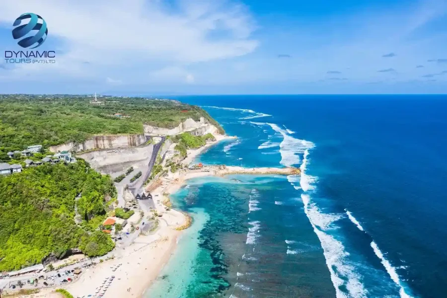 Aerial view of Kuta Beach Bali with turquoise waters, lush cliffs, and winding coastal road