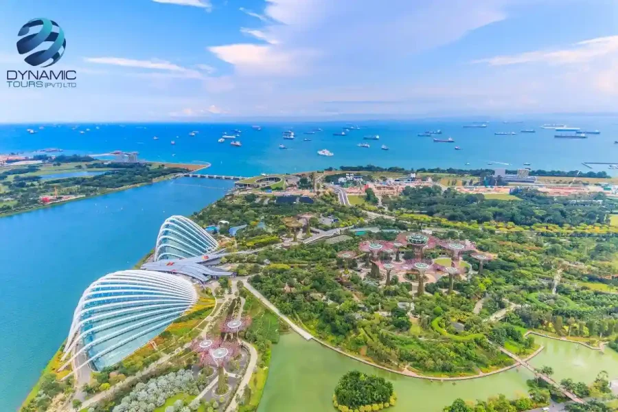 Aerial view of Singapore Gardens by the Bay with Supertree Grove, Flower Dome, Cloud Forest, and ships in the Singapore Strait