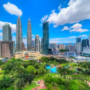 Travel poster featuring Kuala Lumpur skyline with Petronas Twin Towers, modern skyscrapers, and lush green park under bright blue sky